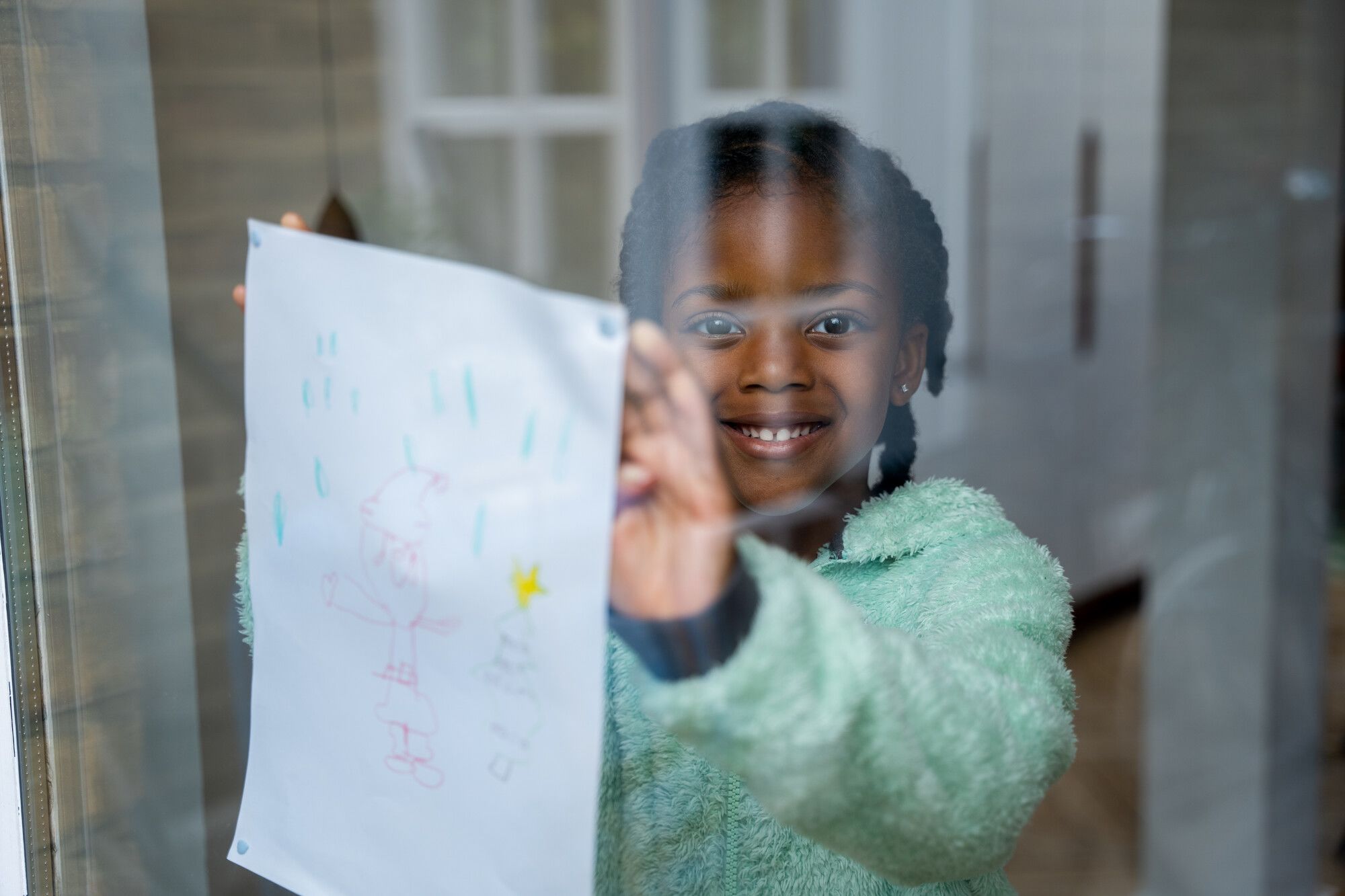 A young girl holding up a drawing