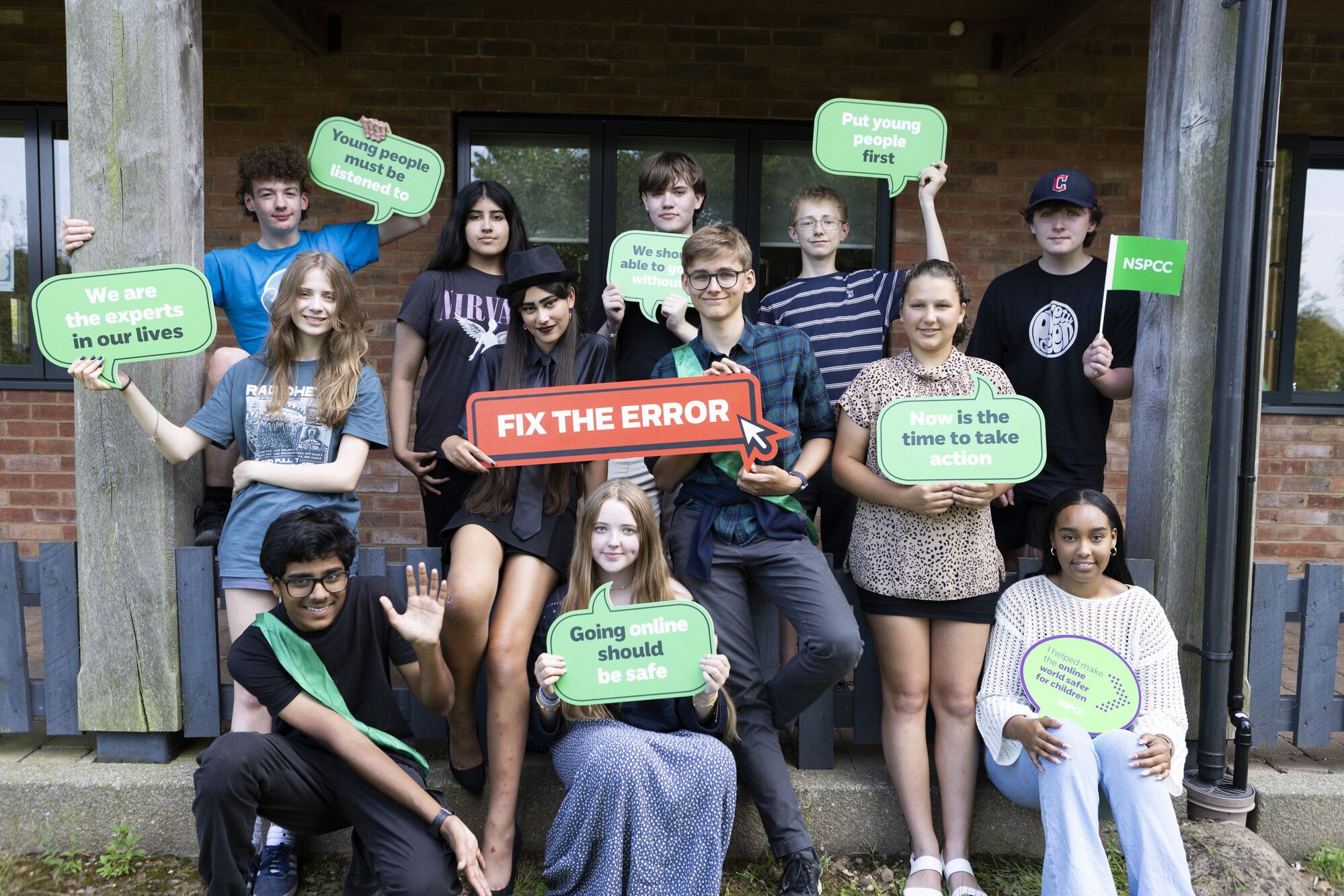 12 young people holding signs that say 'Young people must be listened to', 'We are the experts in our lives', 'Fix the error', 'Going online should be safe', 'Now is the time to take action' and 'put young people first'