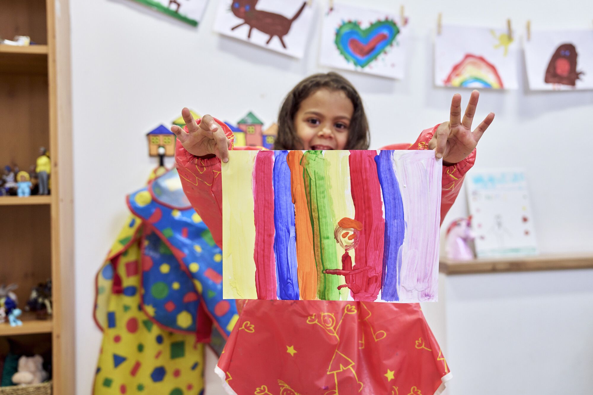 A young girl holding up a drawing